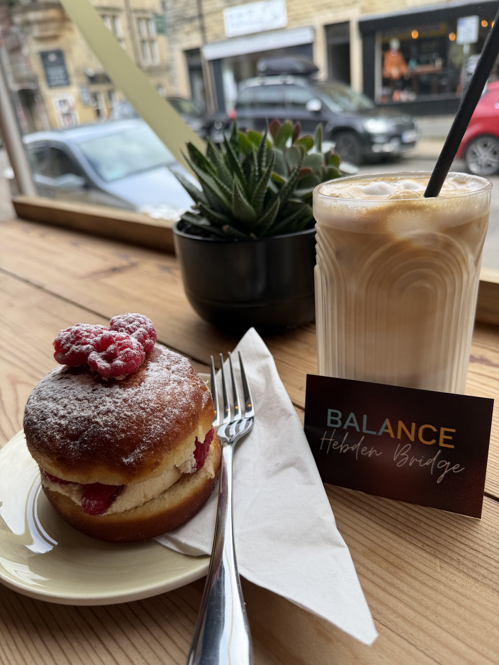 Coffee and a strawberry doughnut at a window table inside BALANCE